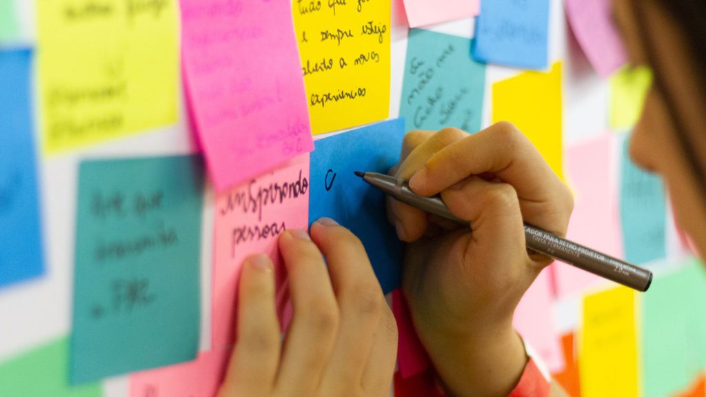 stock photo of someone writing on post-it notes on a wall