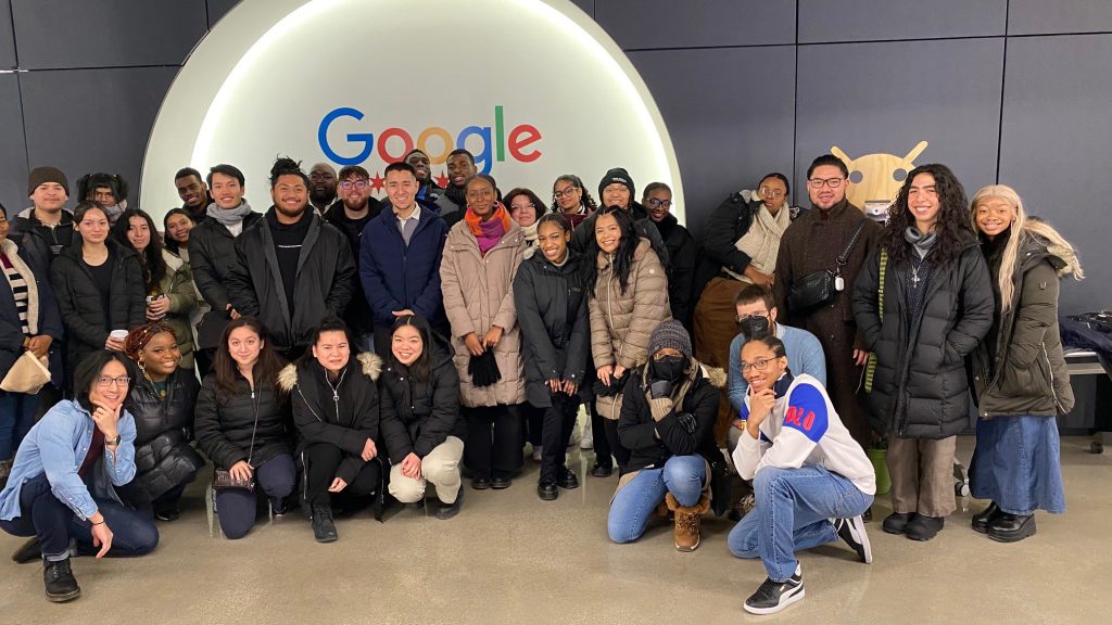 Students, alumni and Google employees in front of Google sign.