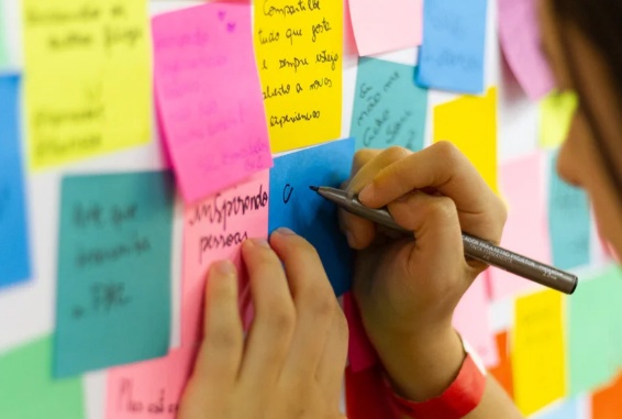 stock photo of person writing on post-it notes on a wall