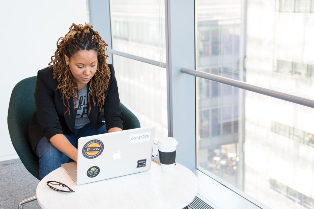 An African American woman sitting in front of a laptop. Image credit goes to WOCinTech @ nappy.co